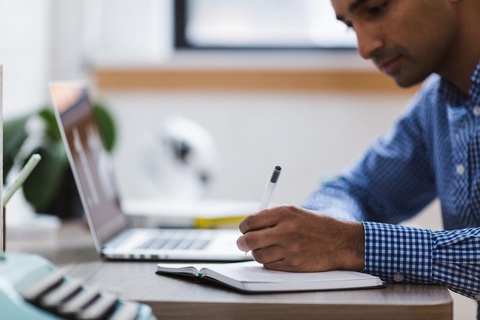 A man sitting at desk working on a laptop