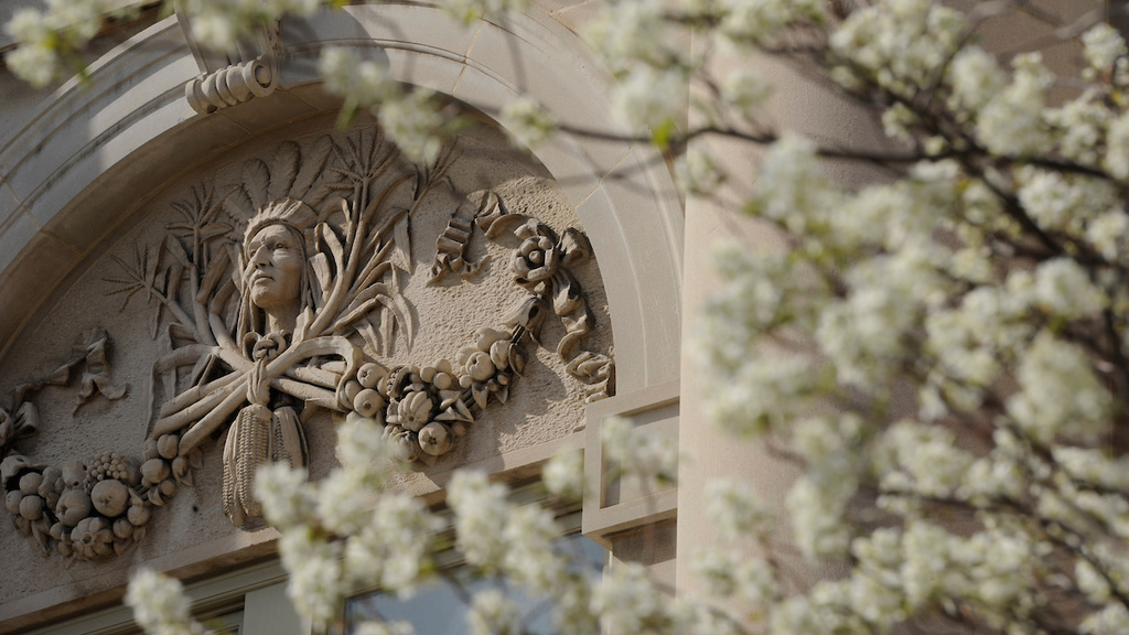 A carving in a building on campus with flowers in front
