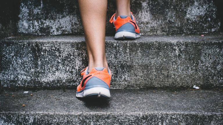 Close up of someone's feet in athletic shoes walking up stairs